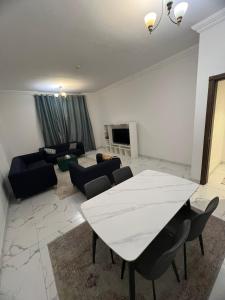 - un salon avec une table et des chaises blanches dans l'établissement 2BHK apt. oasis tower, à Ajman