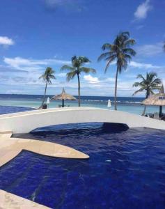 a swimming pool on the beach with palm trees and the ocean at A Hidden Gem in the Caribbean Paradise in María Grande