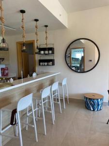 a kitchen with a bar with white stools and a mirror at A Hidden Gem in the Caribbean Paradise in María Grande