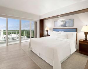 a bedroom with a large white bed and large windows at The Westin Resort Guam in Tumon