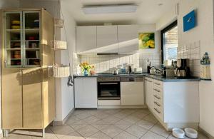 a kitchen with white cabinets and white appliances at Ferienhaus DEICHBLICK in Tossenserdeich