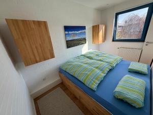a small bedroom with a blue bed and a window at Ferienhaus DEICHBLICK in Tossenserdeich