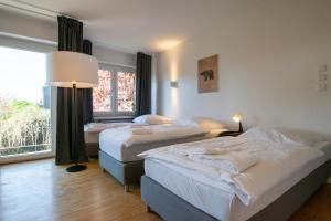 Una habitación con tres camas y una gran ventana. en Tolstov Apartments - 1 , 3 and 4 Room Apartments - 20 min Messe DUS & Airport DUS, en Meerbusch