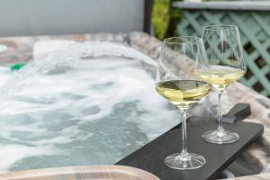 dos copas de vino sentadas en una mesa junto a una bañera en The Front Porch Vacation Rentals, en Bristol