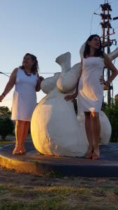 two women in white standing next to a statue at Monoambiente Blanca in Concordia
