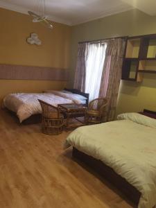 a bedroom with two beds and chairs and a window at Bodhi Homestay in Kathmandu