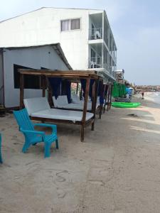 eine Gruppe von Betten und ein blauer Stuhl am Strand in der Unterkunft Cabañas Palos Locos in Barú