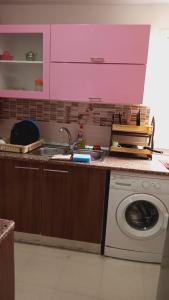 a kitchen with a washing machine and pink cabinets at Kalthoum in Chott Meriem