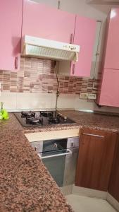 uma cozinha com armários cor-de-rosa e um fogão em Kalthoum em Chott Meriem