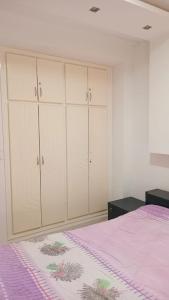 a bedroom with white cabinets and a pink bed at Kalthoum in Chott Meriem