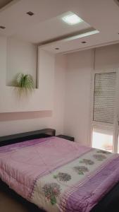 1 dormitorio con 1 cama con manta morada en Kalthoum en Chott Meriem