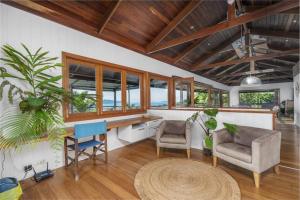 a living room with a desk and chairs and windows at Stu’s Lookout - 4 Bedroom Use - Stunning Views in Mission Beach