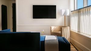 a hotel room with a bed and a chair and a tv at Longfellow Hotel in Portland