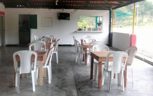 un restaurante con mesas de madera y sillas blancas en Encanto Natural, en Villagarzón