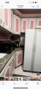 - une cuisine avec des placards roses et blancs et un réfrigérateur dans l'établissement ابراج عثمان اغاخان كورنيش النيل, au Caire