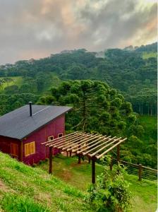 una casa roja con techo de madera en una colina en Refugio Araucária - Gonçalves Mg, en Gonçalves