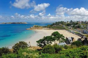 Blick auf einen Strand mit Häusern und das Meer in der Unterkunft Au bord du ruisseau in Saint-Quay-Perros