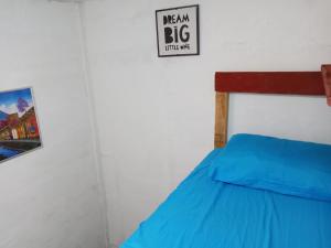 a bedroom with a blue bed with a sign on the wall at Karim Hostel in Guatemala