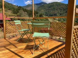two green chairs sitting on a deck with mountains in the background at Mario's Lodge Providencia in El Copey