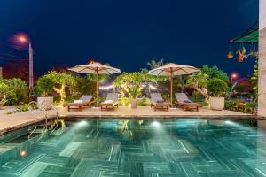 a swimming pool at night with chairs and umbrellas at Villa Dương Hội An in Hoi An