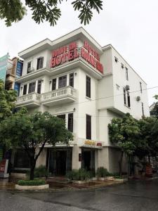een wit gebouw met een rood bord erop bij Khách sạn Hoàng Gia in Thái Bình