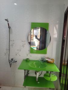 a bathroom with a green sink and a mirror at Hostel Ngọc Liên in Tuy Hoa
