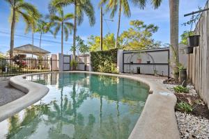 a swimming pool in a yard with palm trees at Oasis - Pool, Wifi & Free Parking in Cairns