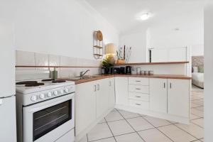 a kitchen with white cabinets and a stove top oven at Oasis - Pool, Wifi & Free Parking in Cairns