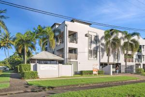 a white building with palm trees in front of it at Oasis - Pool, Wifi & Free Parking in Cairns