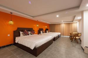 two beds in a room with an orange wall at Sapa Hai Yen Hotel and Apartment in Sa Pả
