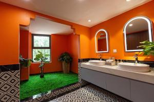 two sinks in a bathroom with orange walls and green grass at Sapa Hai Yen Hotel and Apartment in Sa Pả