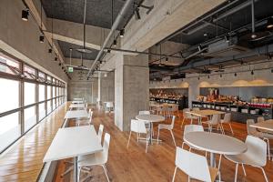 a restaurant with white tables and white chairs at HOTEL MYSTAYS Miyazaki in Miyazaki