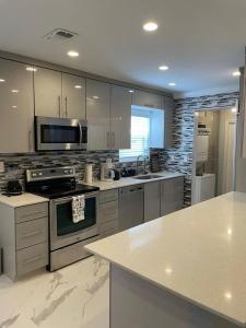 uma grande cozinha com electrodomésticos de aço inoxidável e armários brancos em WONDERFULL NORTH MIAMI em Miami