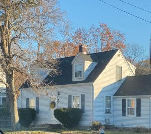 a white house with a black roof at Vibrant City Home 4BD 2BA in Brockton