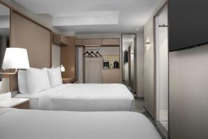 a hotel room with two beds and a hallway at SpringHill Suites by Marriott New York Manhattan Times Square in New York