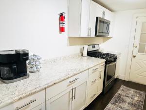 cocina con armarios blancos, fogones y microondas en Vibrant City Home 4BD 2BA, en Brockton