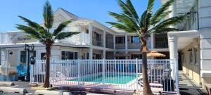a large white house with a swimming pool and palm trees at The Lamplight Inn in Lavallette