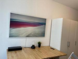 a painting hanging on a wall above a wooden table at Cozy Central Apartment in Trier