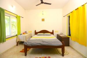 a bedroom with a bed with yellow curtains and a table at Shivalaya Arunachala in Tiruvannāmalai