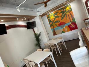 een restaurant met witte tafels en stoelen en een schilderij bij ペンションAloalo in Shirahama
