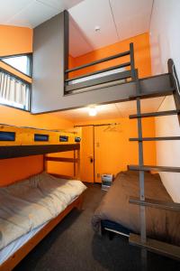 Retopia AIZU磐梯町ゲストハウス : سريرين بطابقين في غرفة مع جدران برتقالية