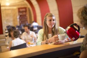 a woman sitting at a table with a cup of coffee at Les Chambres de l'Abbaye in Saintes