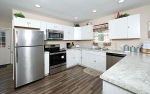 a kitchen with white cabinets and a stainless steel refrigerator at Farmhouse Retreat in Sevierville