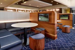 a waiting room with a tv and a table andools at Courtyard by Marriott Charlottesville in Charlottesville