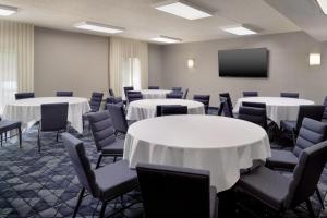a conference room with tables and chairs and a screen at Courtyard by Marriott Charlottesville in Charlottesville