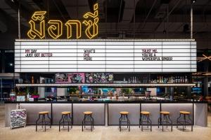 a bar with bar stools in a restaurant at Moxy Bangkok Ratchaprasong in Bangkok