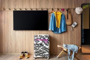 a room with a tv and a chair and clothes at Moxy Bangkok Ratchaprasong in Bangkok