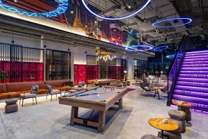 a ping pong table in a room with tables and chairs at Moxy Bangkok Ratchaprasong in Bangkok