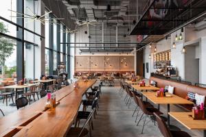 an empty restaurant with wooden tables and chairs at Moxy Bangkok Ratchaprasong in Bangkok