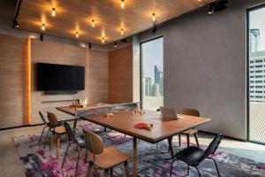 a conference room with tables and chairs and a tv at Moxy Bangkok Ratchaprasong in Bangkok